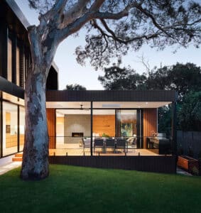 A modern house with a large tree in the back yard, featuring brandingArc design elements.