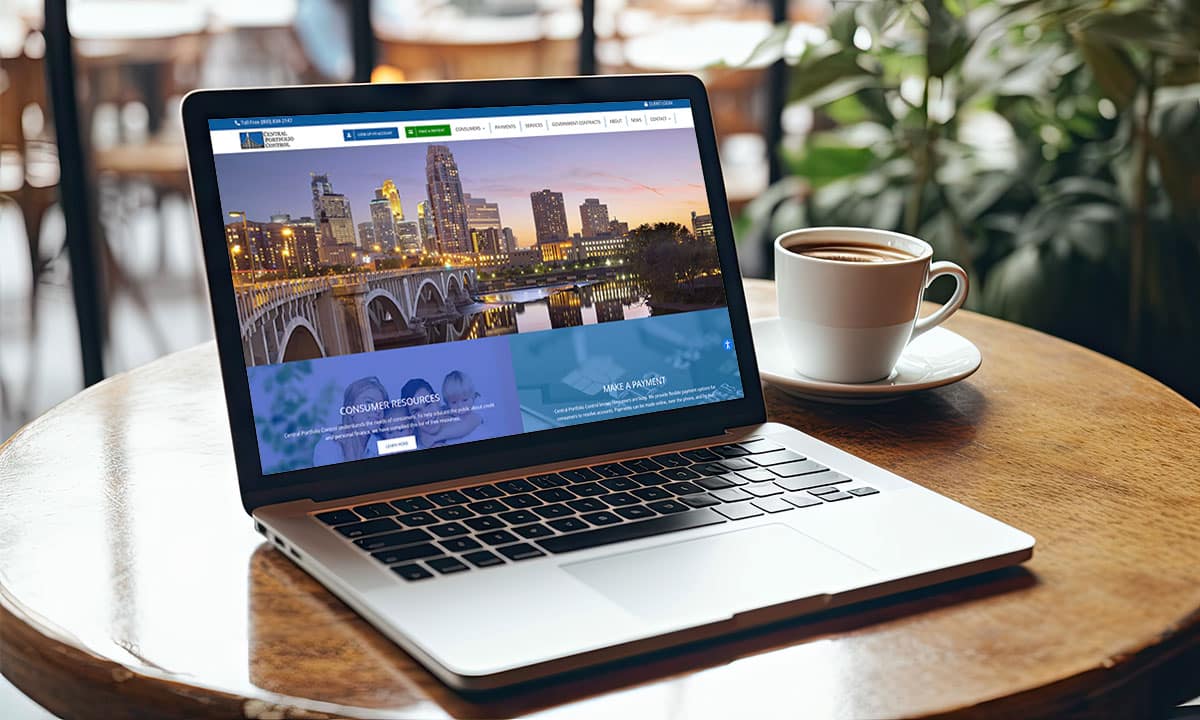 A brandingArc laptop sits on a table with a cup of coffee.