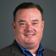 A man in a blue shirt is smiling for the camera while maintaining his professional reputation. A man in a blue shirt is smiling for the camera while maintaining his professional reputation.