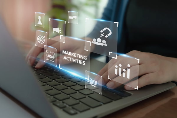 Hands typing on a laptop keyboard with floating icons and the text "Marketing Activities" above.