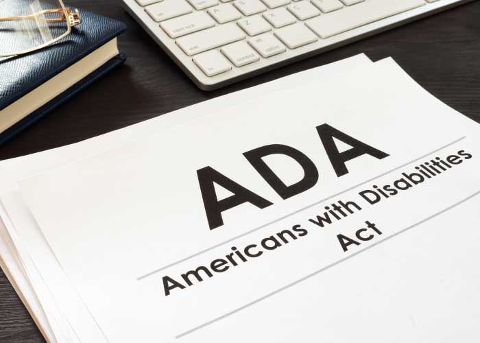 Document titled "ADA Americans with Disabilities Act" on a desk, next to a keyboard and notebook.