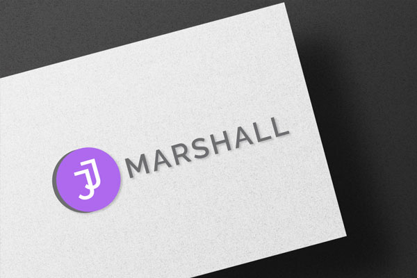 A business card with a gray background featuring a purple circular logo with a stylized letter 'J' and the name 'MARSHALL' in gray letters beside it.